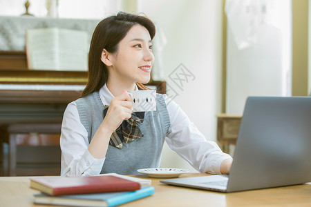 在客厅内喝咖啡学习的女大学生图片