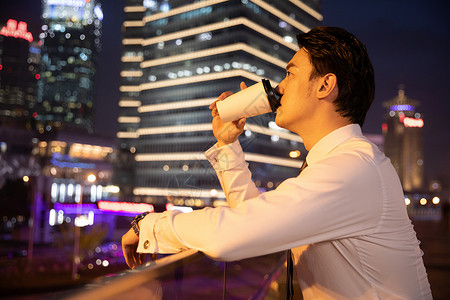 加夜班夜晚都市天桥上的商务男性喝咖啡背景