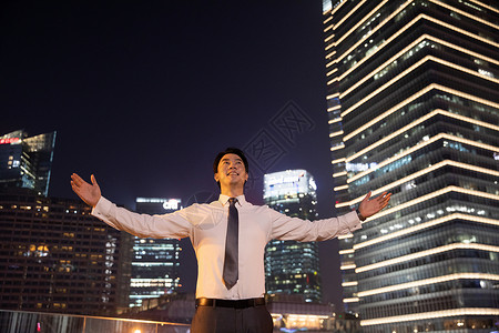 夜晚天桥上的都市商务男性张开双臂高清图片