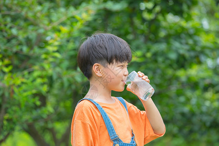 树林前男孩拿着水杯喝水高清图片