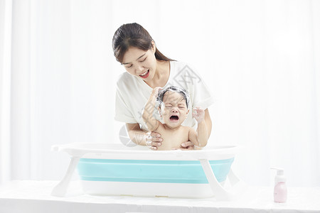 婴儿浴盆年轻妈妈给宝宝洗澡背景