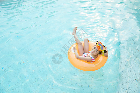 泳池里的人小女孩躺在泳池里的游泳圈上背景