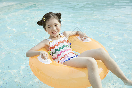 小女孩躺在泳池里的游泳圈上高清图片