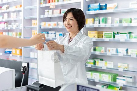 药品注册药剂师打包好药品双手递给顾客背景