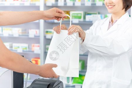 药品注册药剂师打包好药品双手递给顾客背景