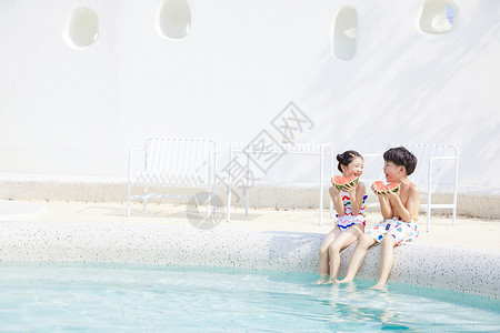 小男孩和小女孩坐在泳池吃西瓜图片