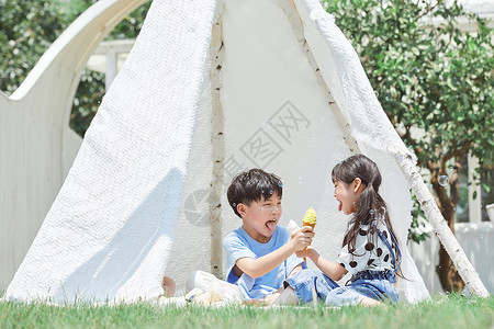 可爱夏日冰淇淋小男孩和小女孩坐在草坪上吃冰淇淋背景