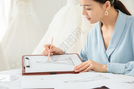 工作中的婚纱设计师绘画设计图的服装设计师特写背景