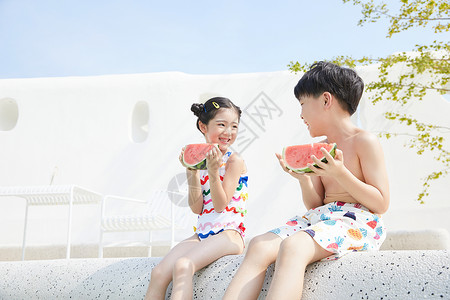 坐在西瓜上人小男孩和小女孩坐在泳池边开心吃西瓜背景