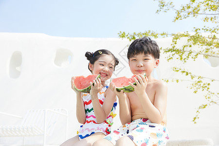 小男孩和小女孩坐在泳池边开心吃西瓜图片