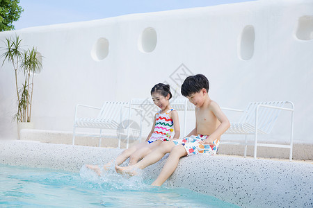 小男孩和小女孩坐在泳池边玩水图片
