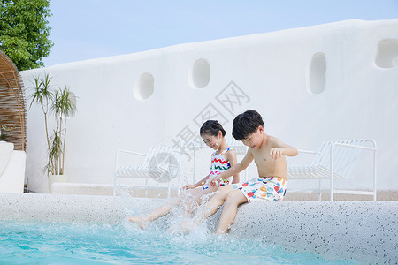 小男孩和小女孩坐在泳池边玩水图片