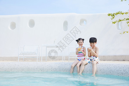 儿童饮品小男孩和小女孩坐在泳池边喝果汁背景
