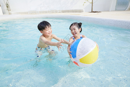 复古泳池球小男孩和小女孩在泳池玩球背景
