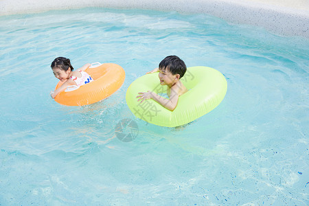 快乐儿童使用游泳圈在泳池玩耍图片