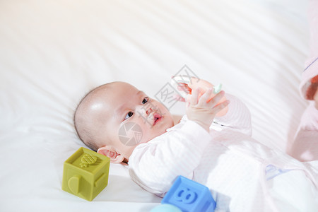 宝宝趴在床上开心的玩球玩玩具背景图片