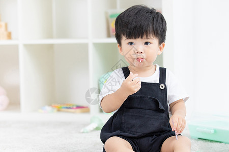 坏人给小孩糖果可爱幼儿宝宝坐地毯上吃糖果背景