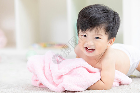 幼儿宝宝裹着浴巾在地毯上嬉戏背景