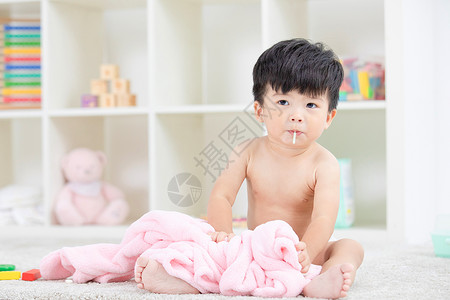 可爱宝宝裹着浴巾在地毯嬉戏背景图片