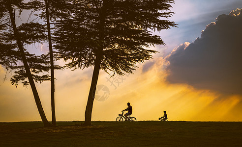 自行车的剪影傍晚夕阳下骑车的父子剪影背景