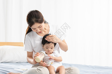 女人喝奶年轻妈妈用奶瓶辅助宝宝喝奶背景