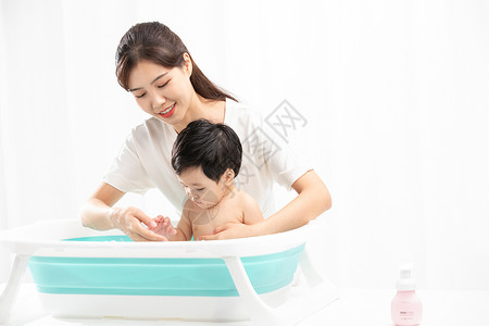婴儿浴盆年轻妈妈给孩子洗澡背景