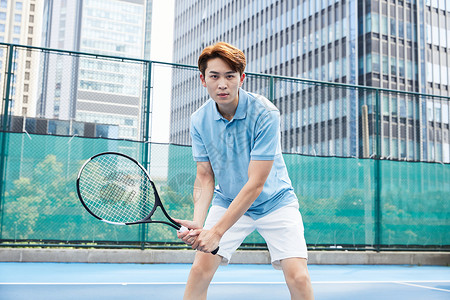 男孩在打网球在网球场打网球的青年男性背景