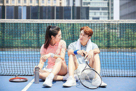坐在网球场上休息的运动男女图片