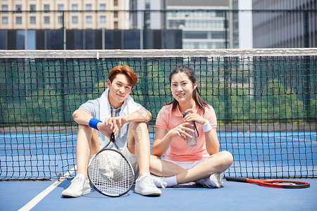 坐在网球场上休息喝水的运动男女图片