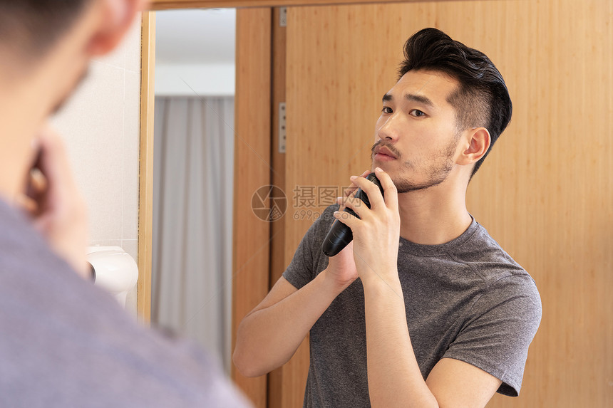 青年男性在洗手间照镜子剃须图片