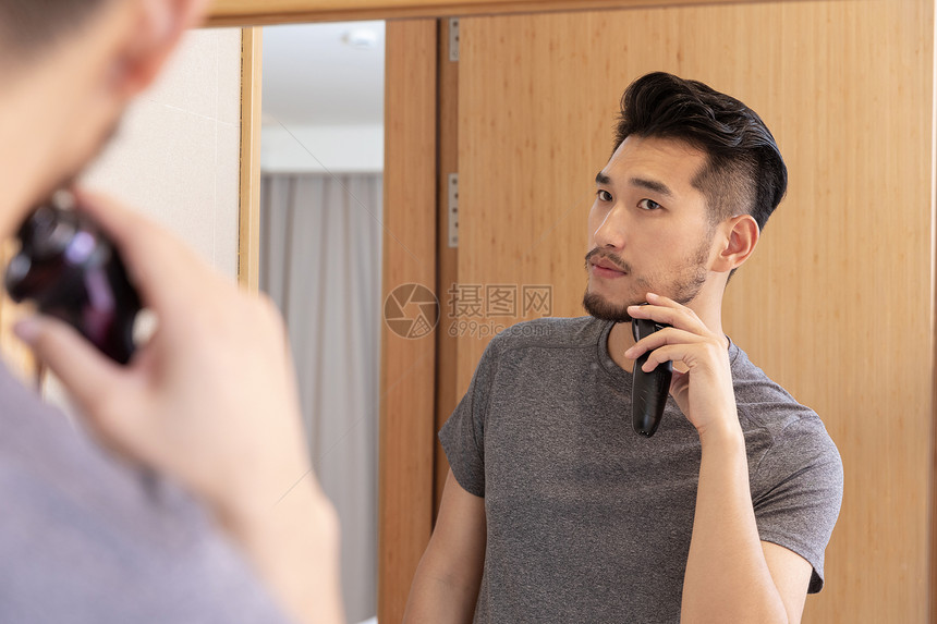 青年男性在洗手间照镜子剃须图片