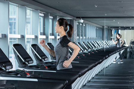 减肥进行中使用跑步机进行跑步训练的健身女性背景