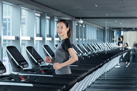 减肥进行中使用跑步机进行跑步训练的健身女性背景