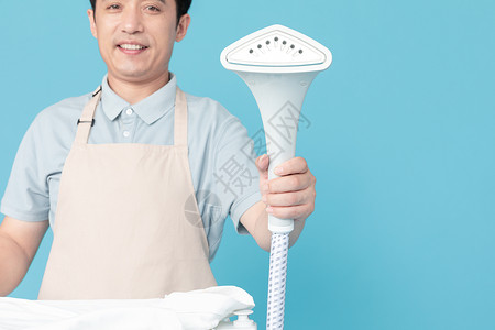 使用挂烫机熨烫衣服的家政服务男性特写背景图片