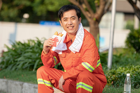 坐在马路旁吃油条的环卫工人背景图片