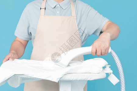使用挂烫机熨烫衣服的家政服务男性背景图片