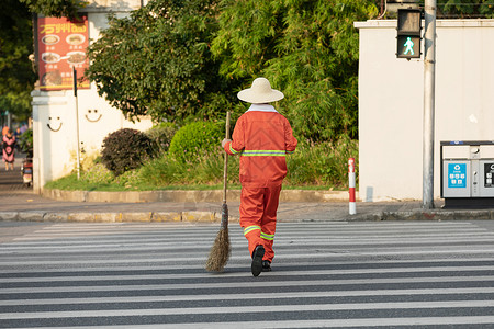 反光路锥拎着垃圾袋与扫帚的环卫工人过马路背景