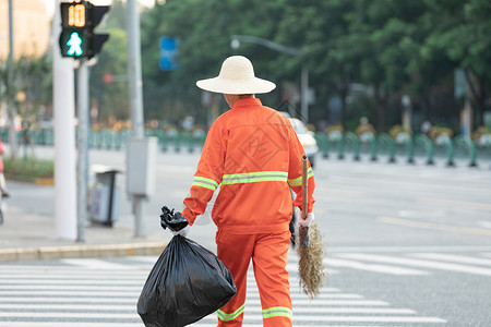 垃圾整理拎着垃圾袋与扫帚的环卫工人过马路背景