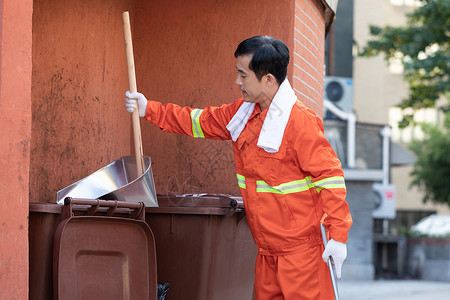 使用簸箕倒垃圾的环卫工人背景图片