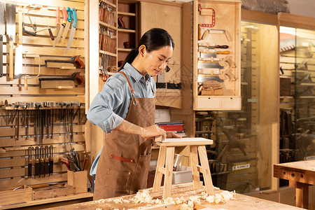 木匠美女工人打磨木头凳子背景图片