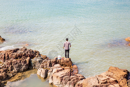 礁石上海钓的男人背景图片