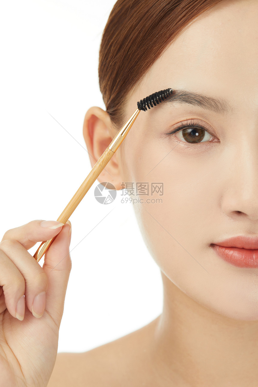 使用睫毛刷刷眉毛的女性图片