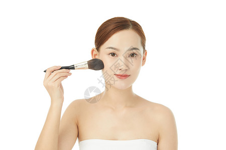 女性使用化妆刷刷脸颊图片