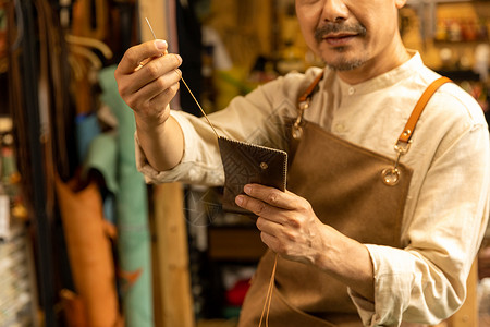中年男性皮匠缝制真皮钱夹图片