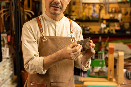 中年男性皮匠缝制真皮钱夹图片