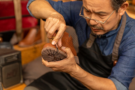 男性皮匠拿刻刀修理皮鞋背景图片