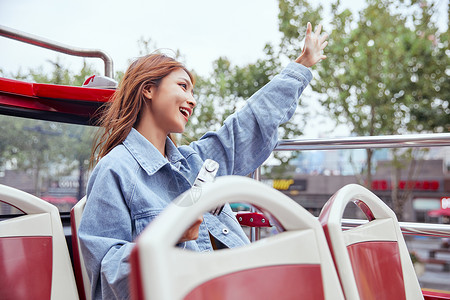 坐观光大巴旅游拍照的年轻女孩图片