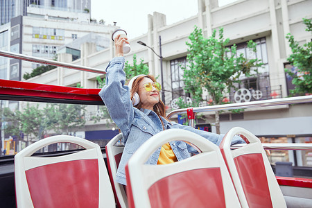 坐观光大巴旅游伸手欢呼的年轻女孩背景图片