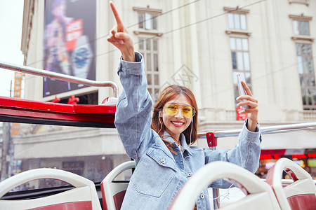 在观光大巴上用手机自拍的女青年图片