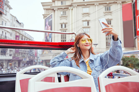 在观光大巴上用手机自拍的女青年背景图片